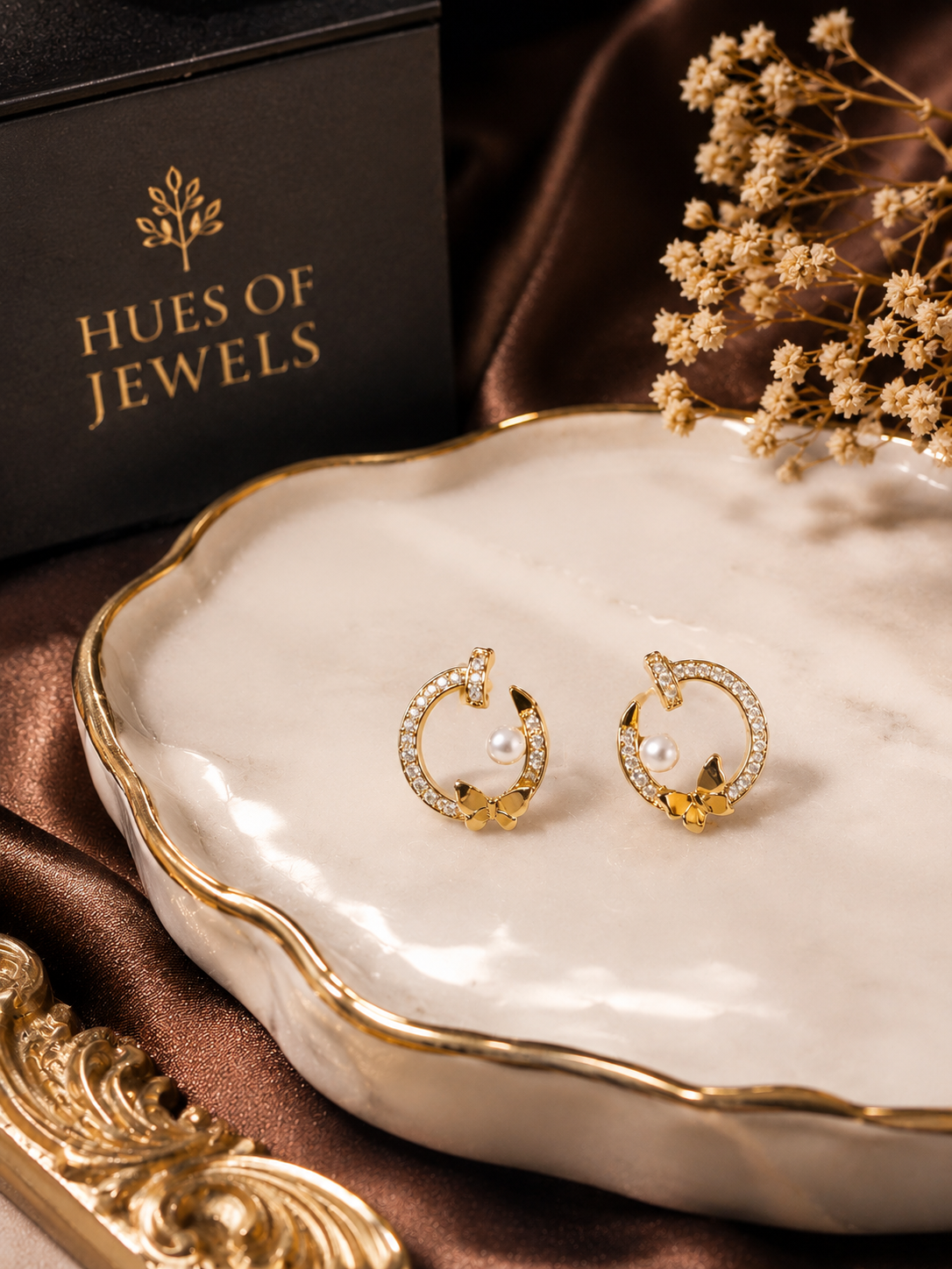 Anti tarnish earrings with pearls on a white dish, branded 'Hues of Jewels'.