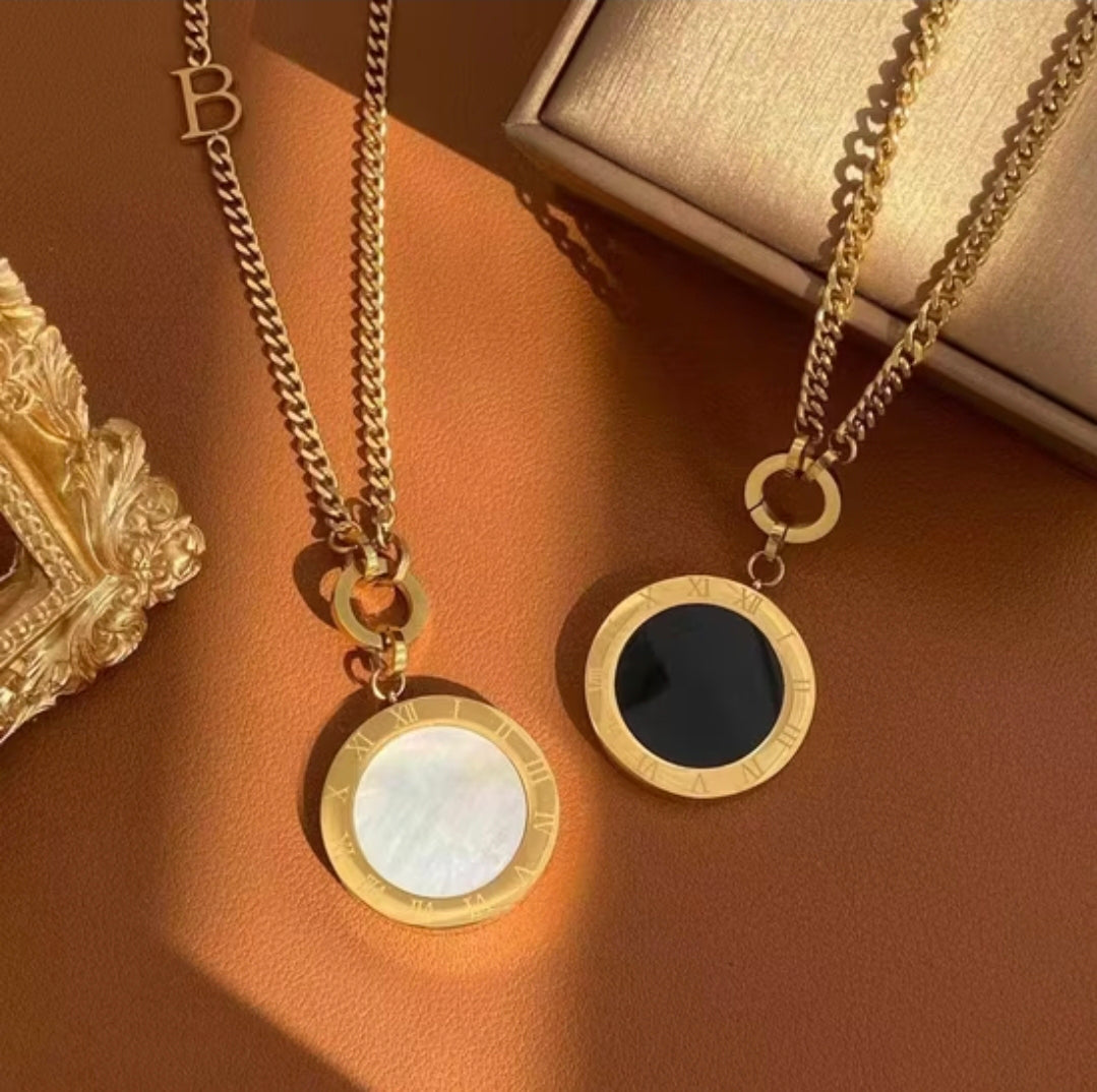 Two gold necklaces with circular pendants on a brown surface.