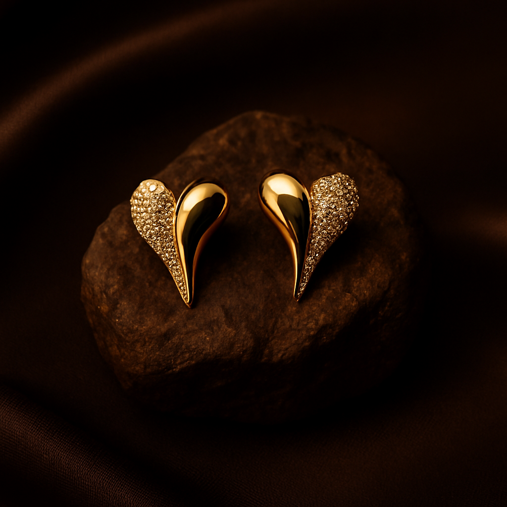 Gold heart-shaped earrings on a dark stone surface