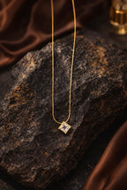 Gold necklace with a diamond pendant on a dark stone surface