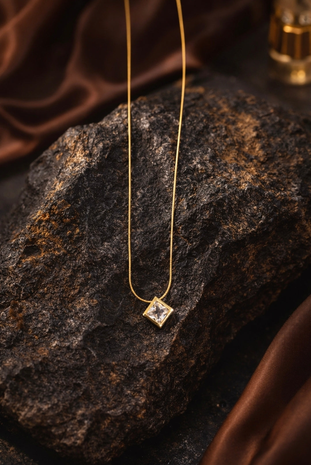 Gold necklace with a diamond pendant on a dark stone surface