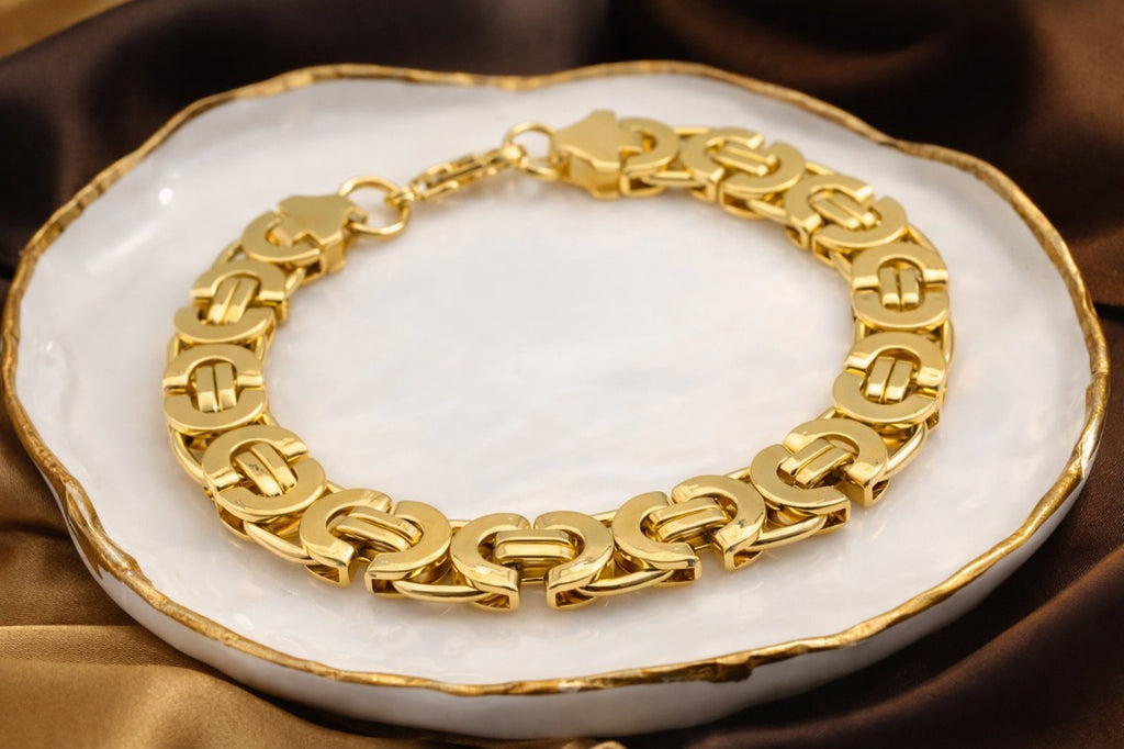 Gold chain bracelet on a white dish with a brown fabric background
