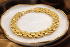 Gold chain bracelet on a white dish with a brown fabric background