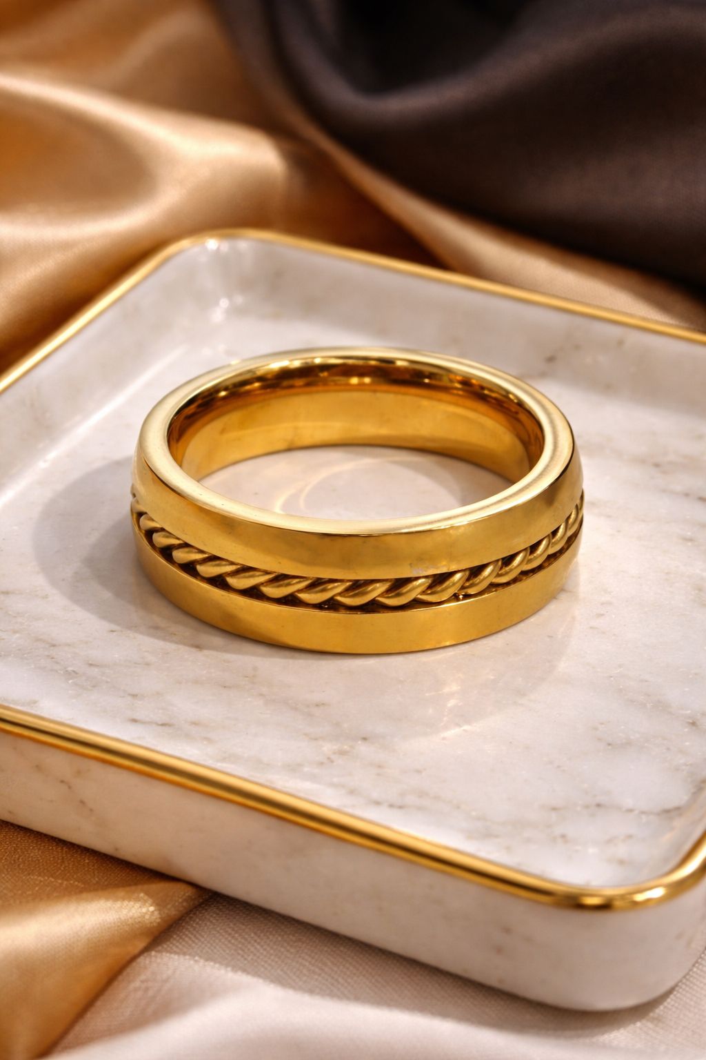 Gold ring with braided design on a marble tray