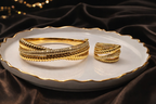 Gold bracelets on a white plate with a dark fabric background