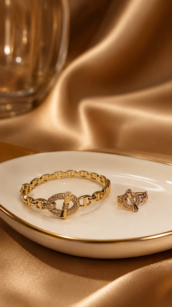Gold bracelet and matching ring on a white dish with a gold background