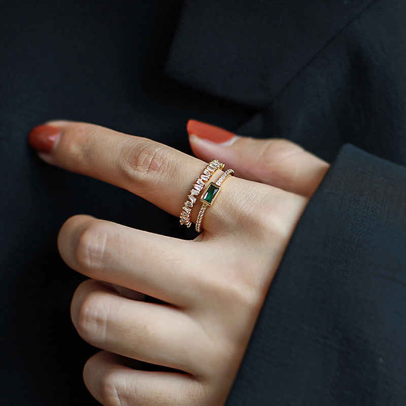 Close-up of a hand wearing Emerald with gemstones against a dark background