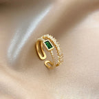 Gold ring with a green gemstone on a beige fabric background