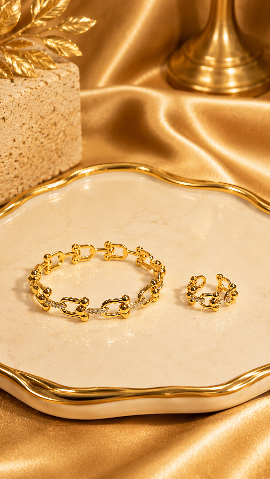 Gold bracelet and ring on a decorative plate with a gold background