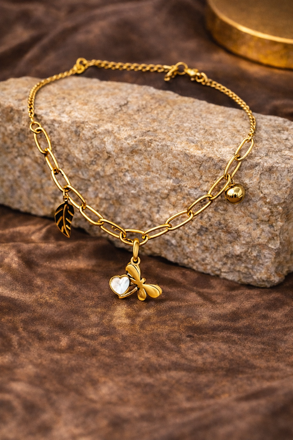 Gold neck chain with charms on a stone surface
