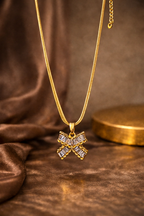 Gold necklace with a bow pendant on a brown fabric background