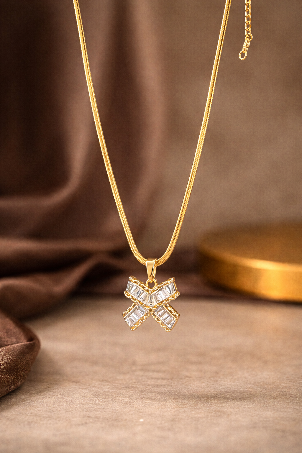 Gold necklace with a diamond pendant on a brown fabric background