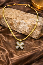 Snake Chain necklace with a cross bow pendant on a brown fabric background