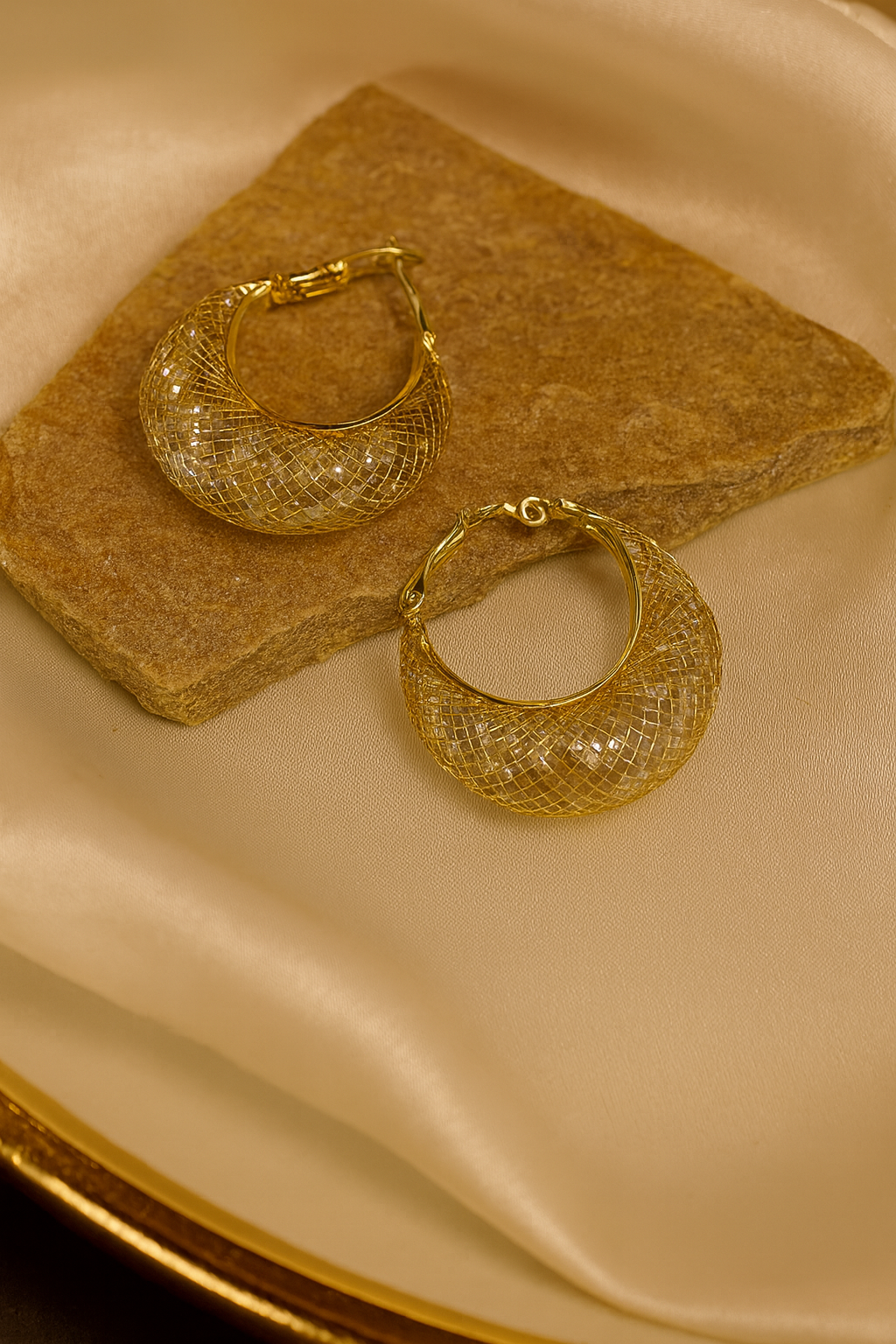 Pair of gold hoop earrings on a beige fabric background
