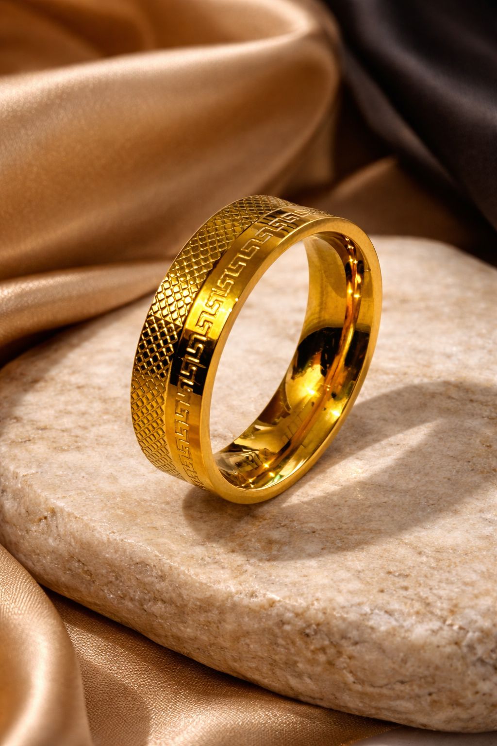 Gold plated ring with textured design on a stone surface