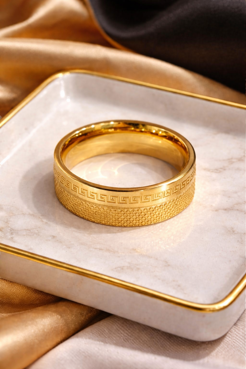 Gold plated ring with intricate design on a white dish with gold rim