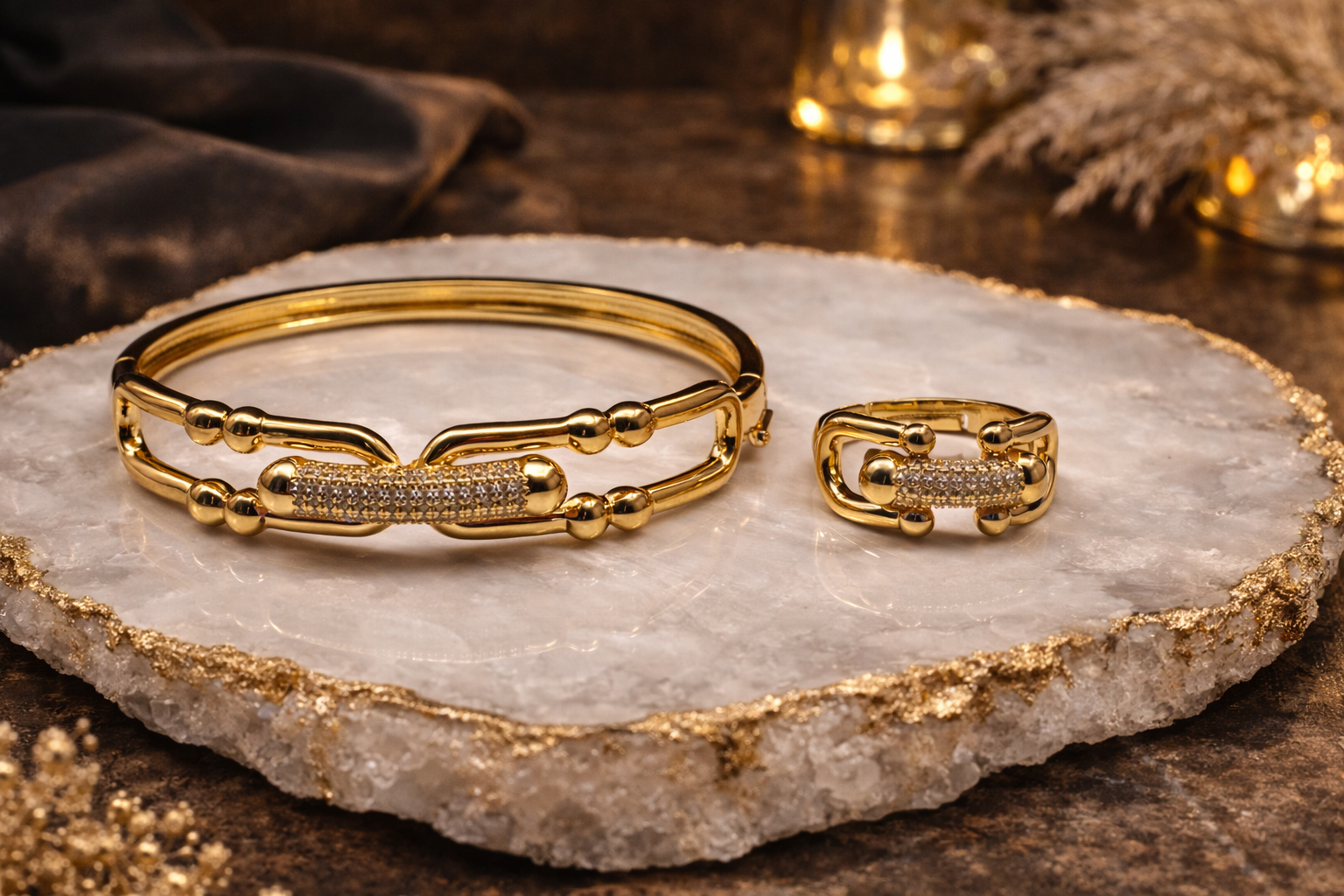 Gold bracelet and ring on a decorative stone surface with warm lighting