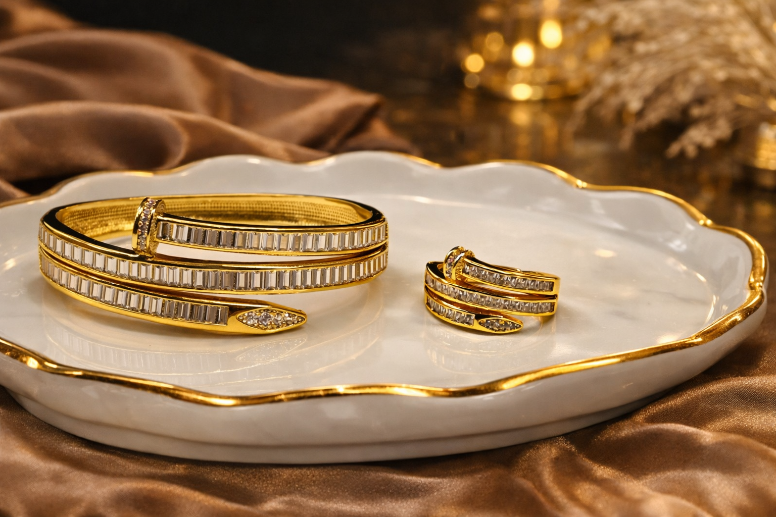 Gold 3 layer nail bracelets and ring on a decorative white dish with gold rim