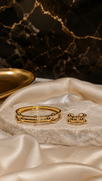 Gold bracelet and ring on a marble surface with a dark marble background