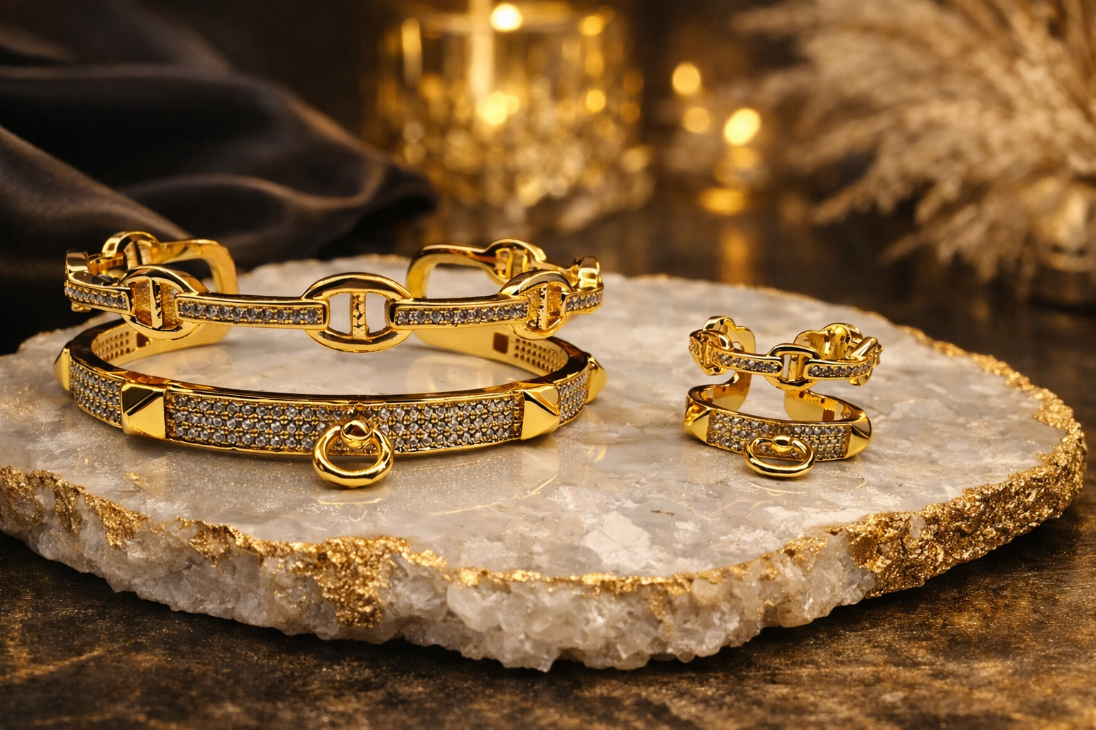 Gold jewelry set including bracelets and rings on a decorative stone surface.