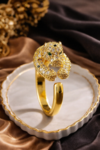 Gold panther-shaped ring on a decorative plate with a brown fabric background