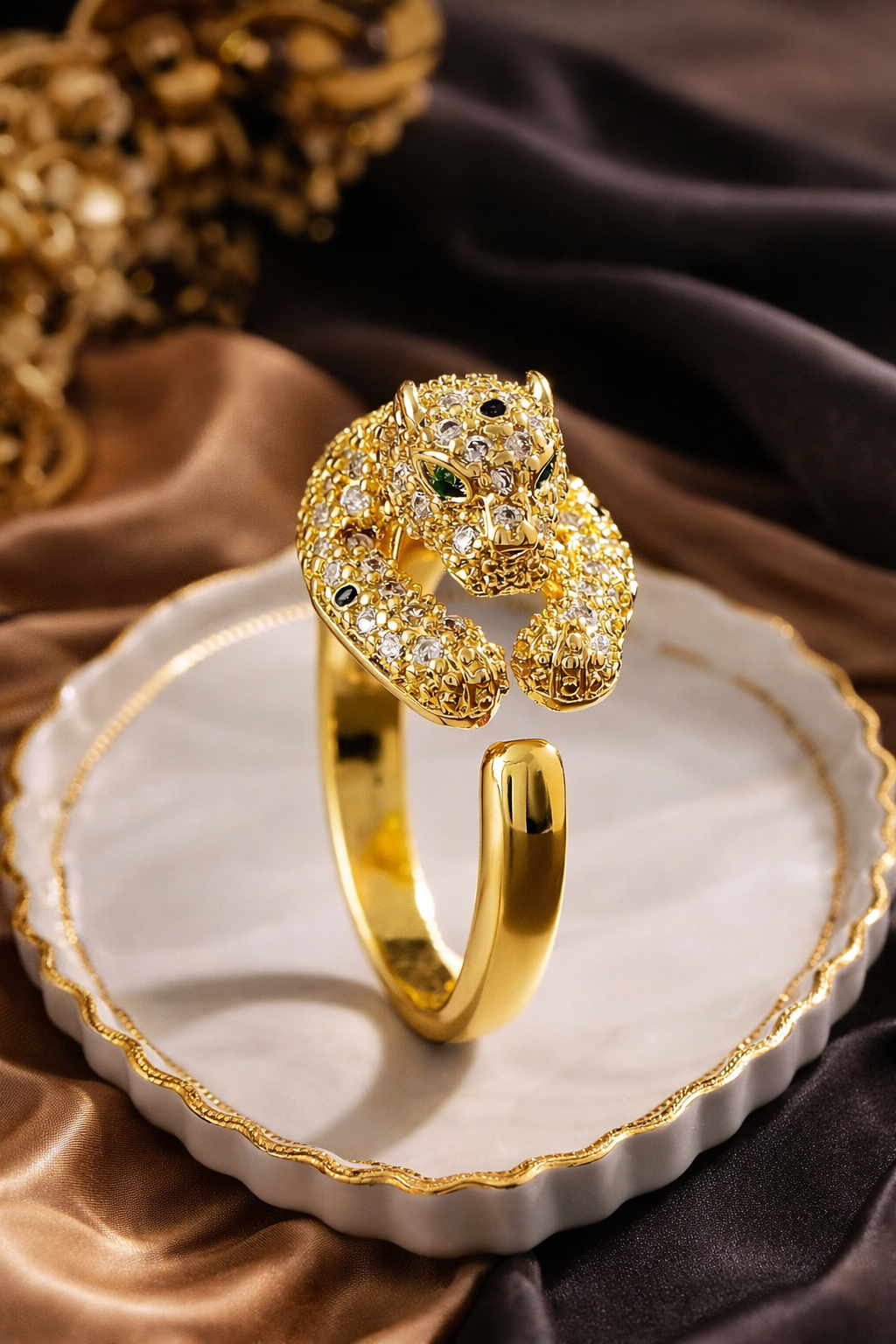 Gold panther-shaped ring on a decorative plate with a brown fabric background