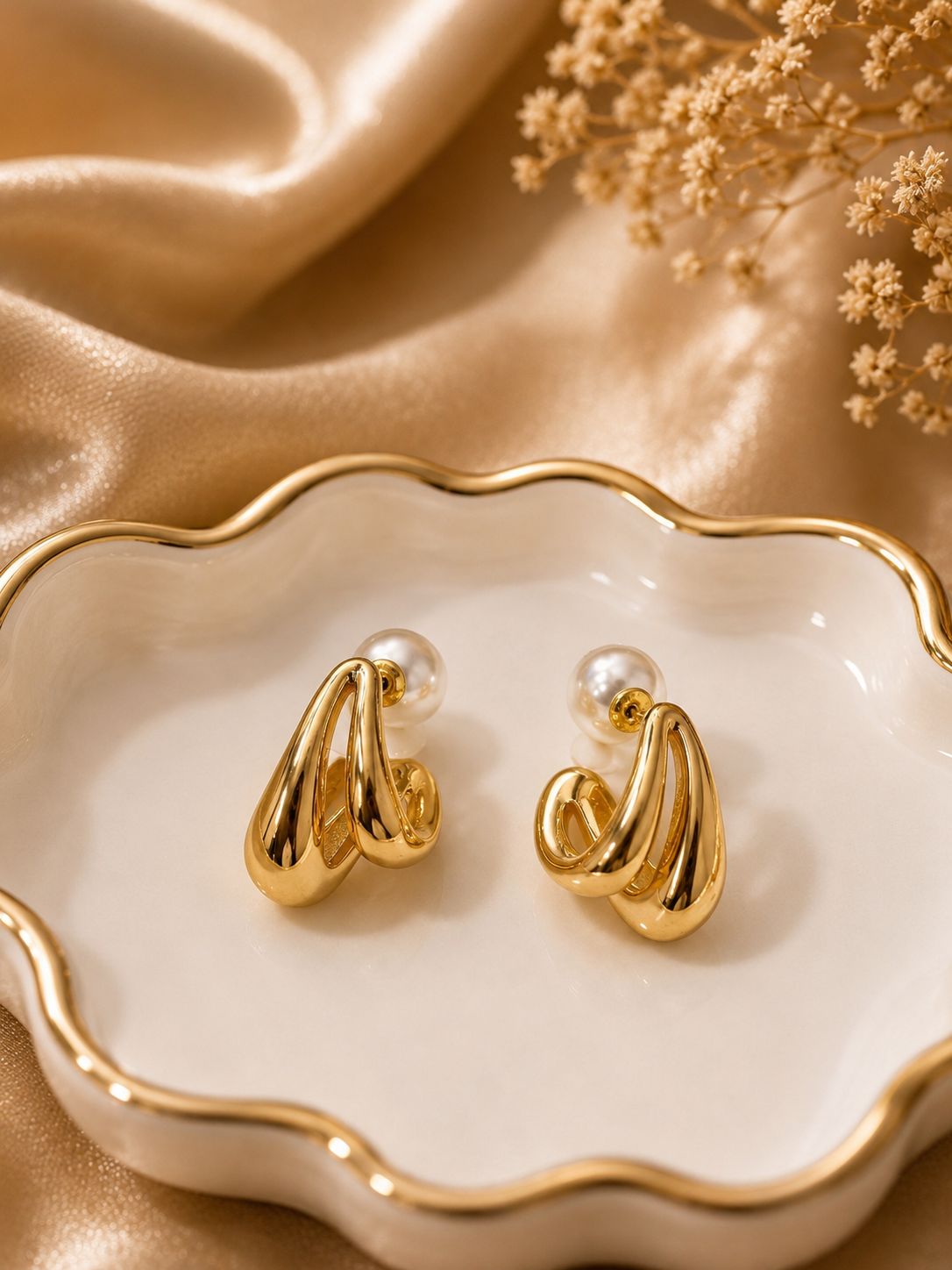 Gold earrings on a decorative dish with a gold background