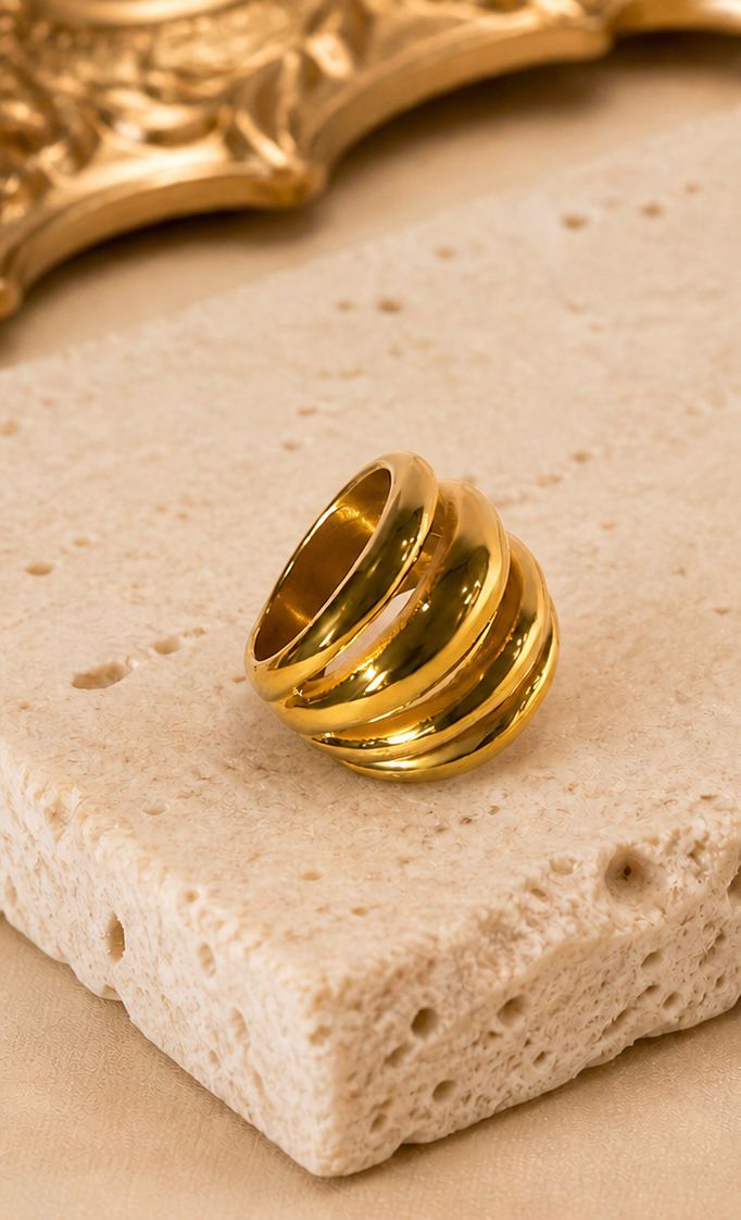 Gold ring with four bands on a textured beige surface - Quadra Finger Ring