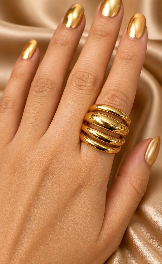 Hand wearing a gold ring with matching nail polish on a satin background - Quadra Finger Ring