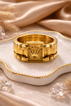 Gold ring with a prominent crown design on a beige fabric background