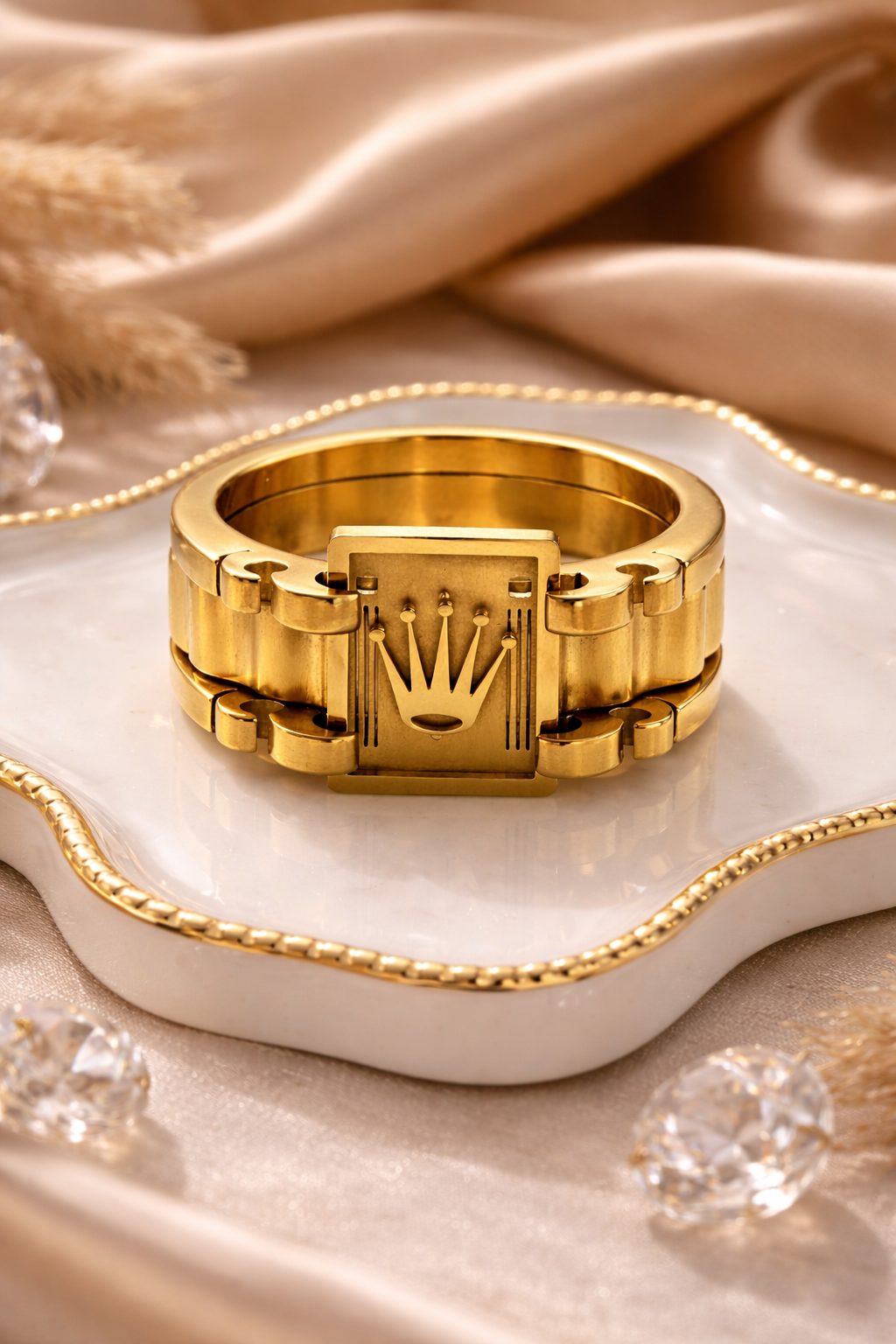 Gold ring with a prominent crown design on a beige fabric background