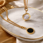 Gold necklaces with round pendants on a marble surface