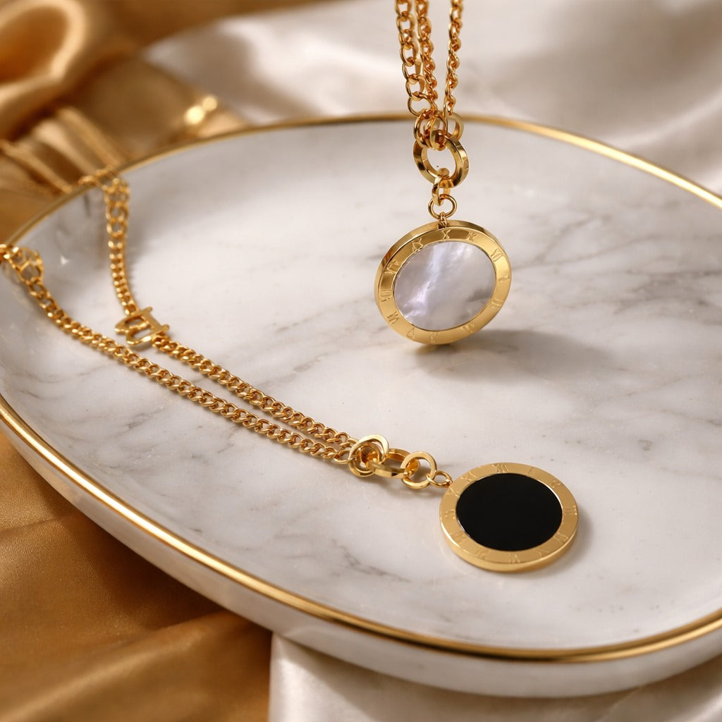 Gold necklaces with round pendants on a marble surface