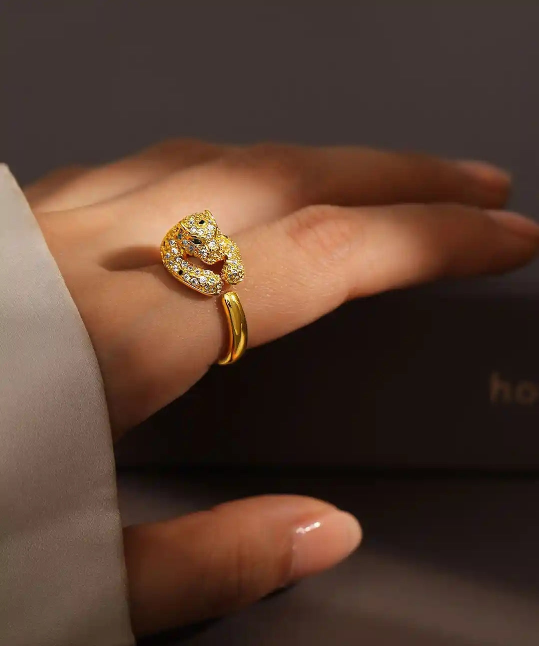 Gold running panther adjustable ring with diamond accents on a hand against a dark background