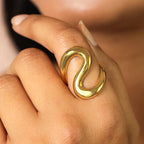 Gold ring with a snake-like design on a finger
