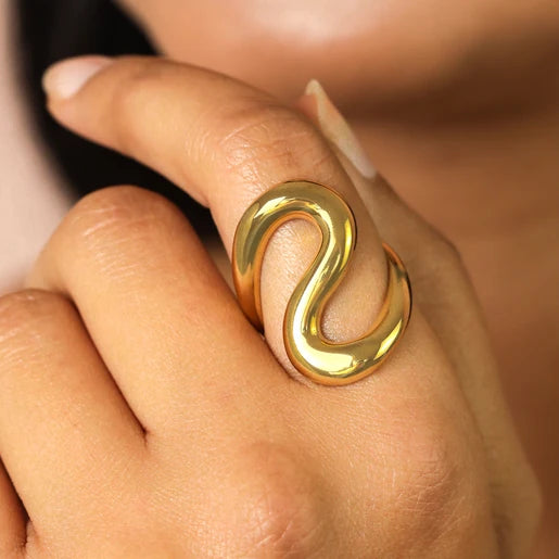 Gold ring with a snake-like design on a finger