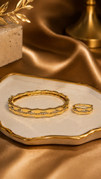 Gold bracelet and ring set on a decorative dish with a gold background