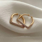 Gold square ring with embedded stones on a soft fabric background