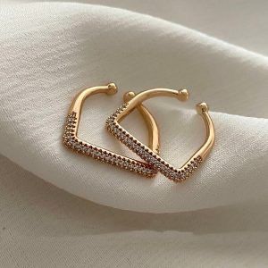 Gold square ring with embedded stones on a soft fabric background