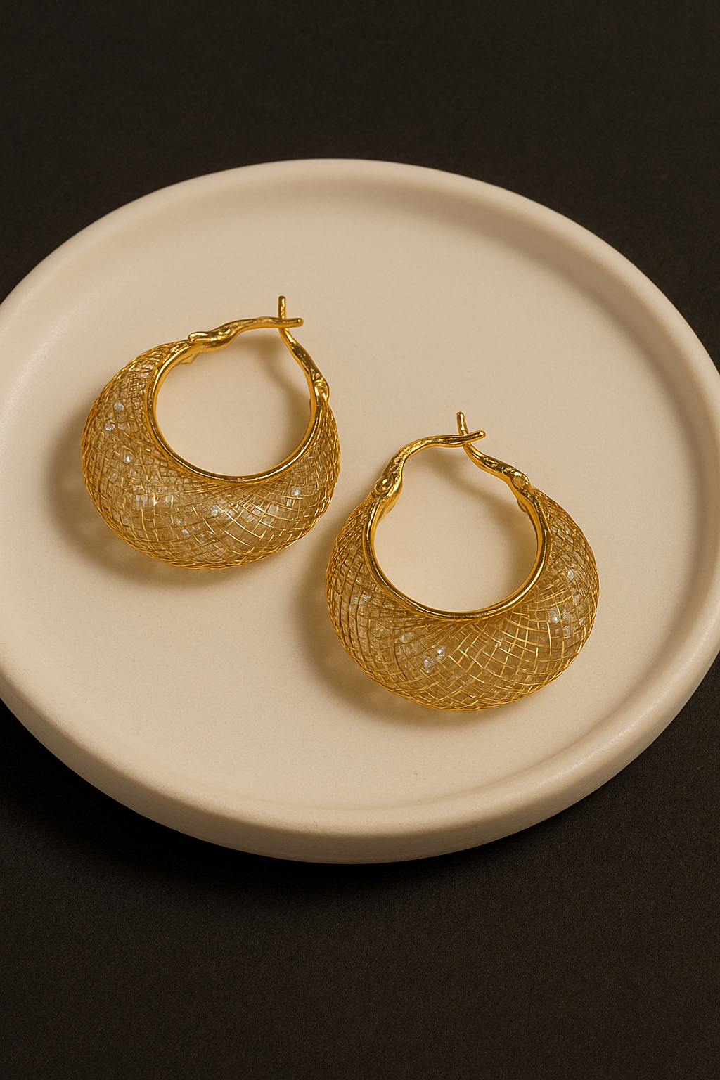 Gold Stellar Mesh Hoops earrings on a beige plate with a dark background