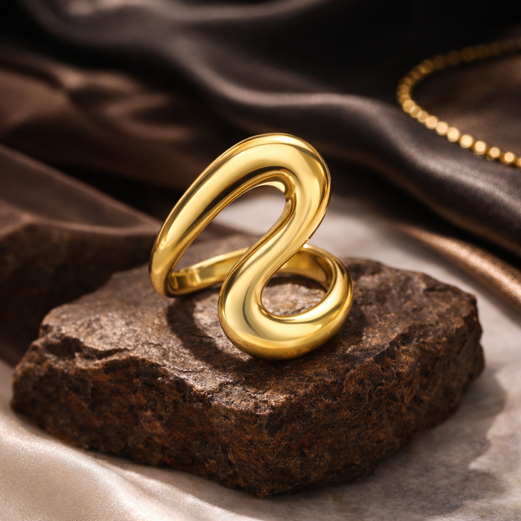 Gold spiral ring on a textured stone surface with a brown fabric background
