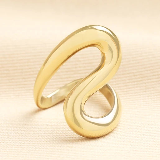 Gold ring with a wavy design on a beige background