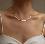 Gold snake chain on a model against a neutral background