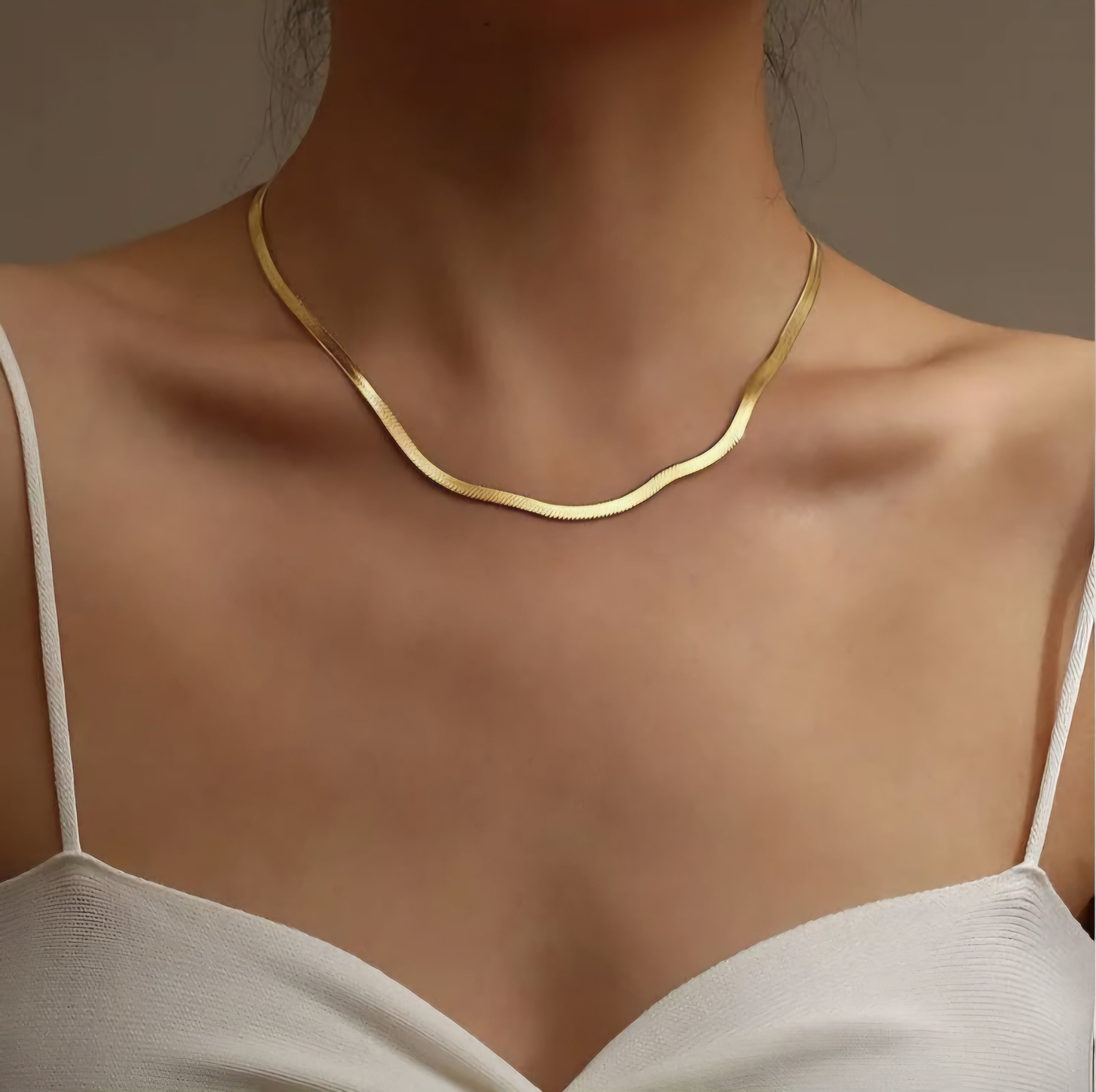 Gold snake chain on a model against a neutral background