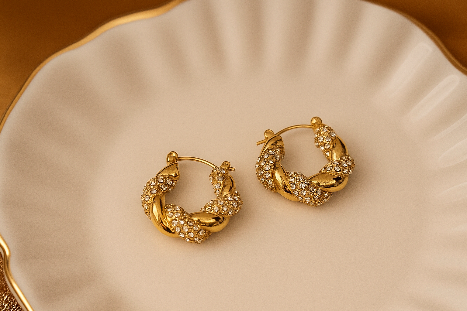 Gold hoop earrings on a decorative beige plate