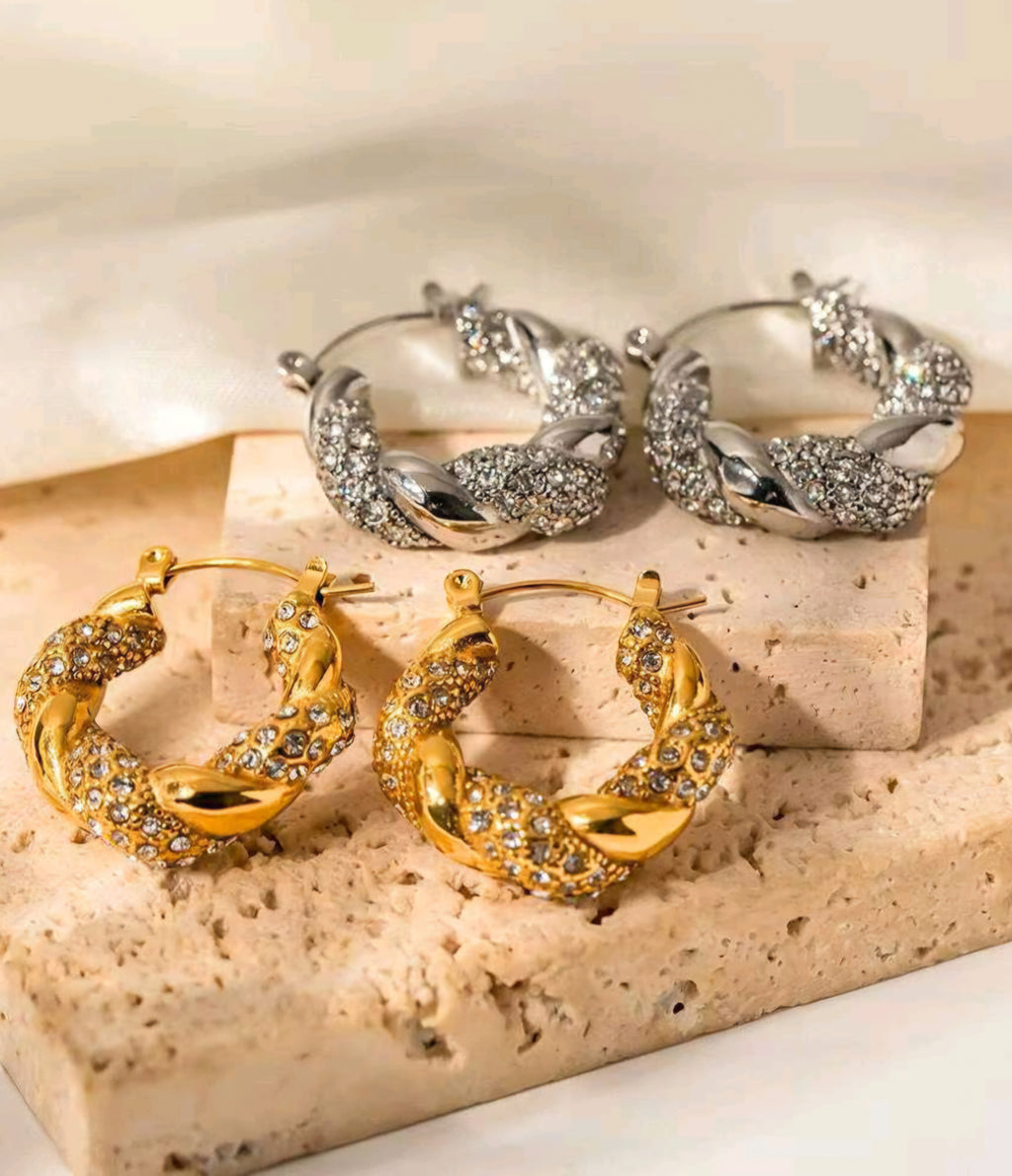 Pair of gold hoop earrings on a beige stone surface.