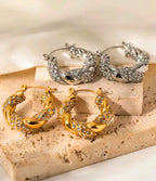 Pair of gold hoop earrings on a beige stone surface.