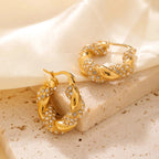 Gold hoop earrings with gemstones on a beige fabric background